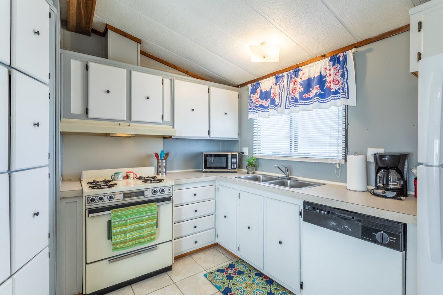 Guest house kitchen with white cabinets, a range and a dishwasher.