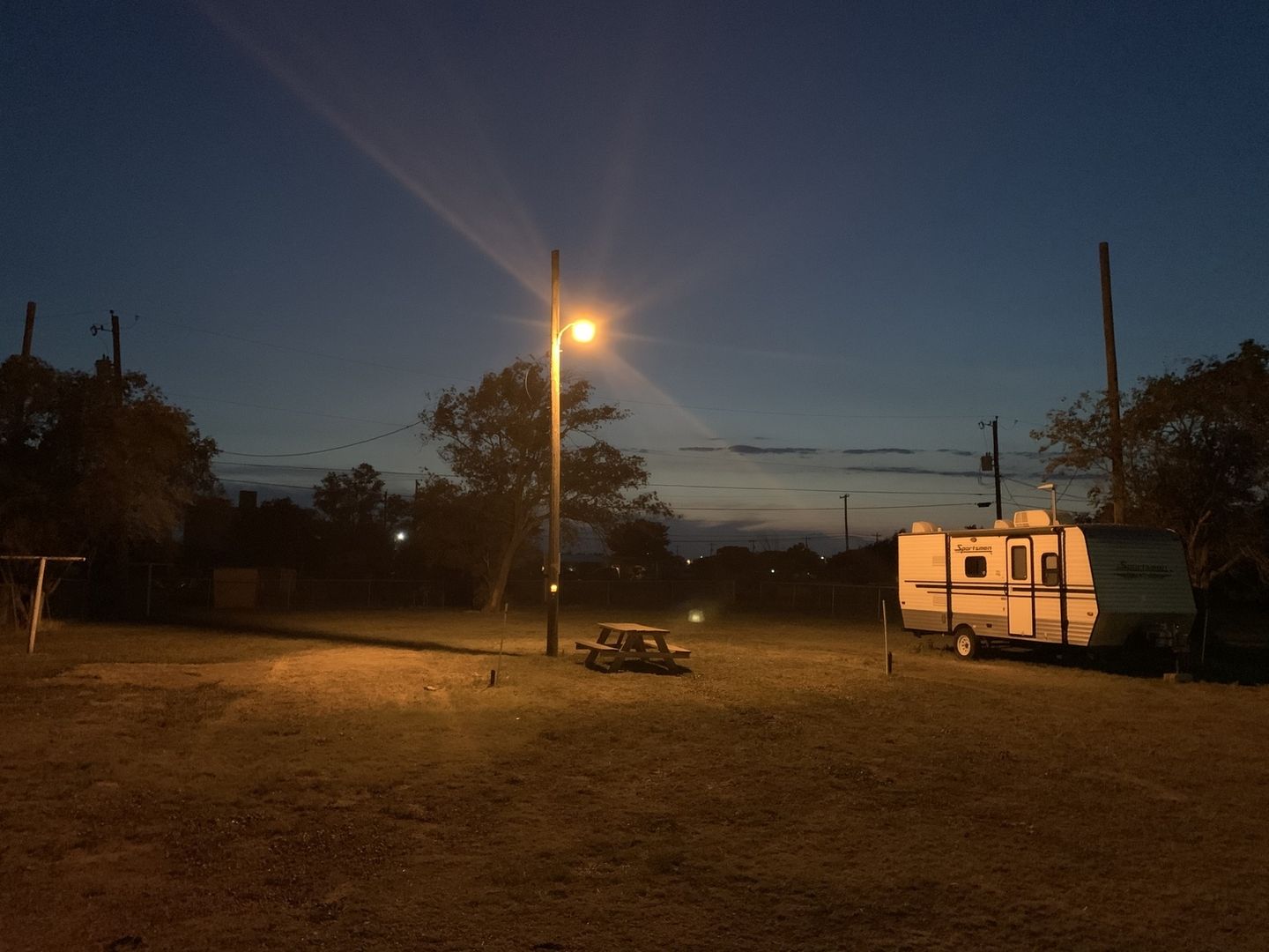 Travel trailer under a pole light at night.