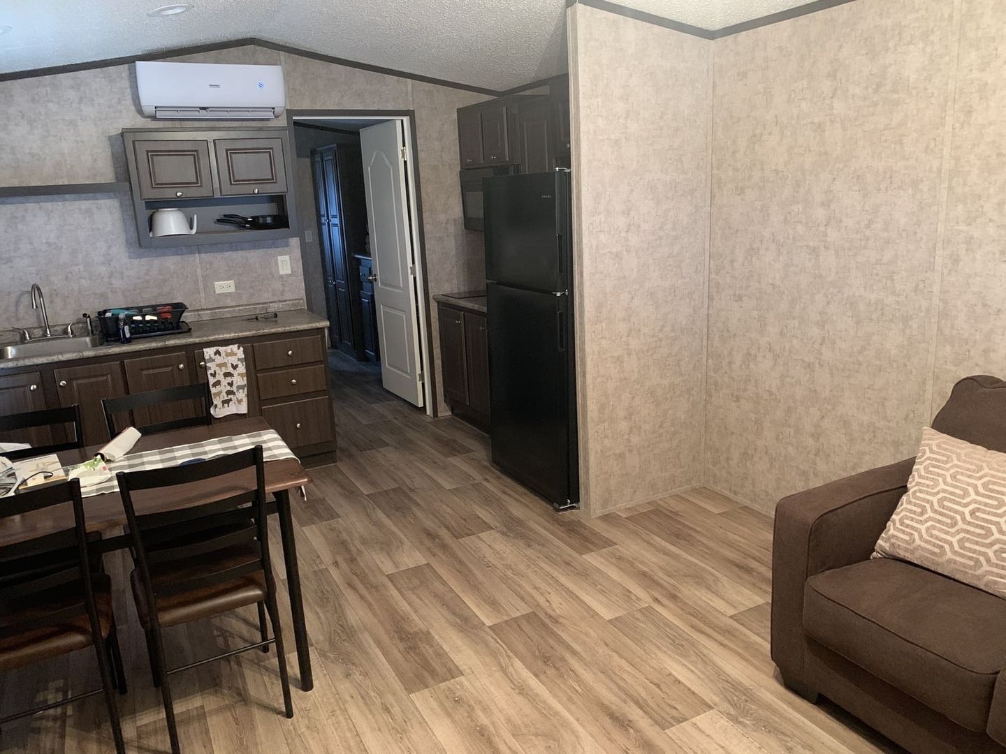 Tiny cabin kitchen, dining table and loveseat in one room.