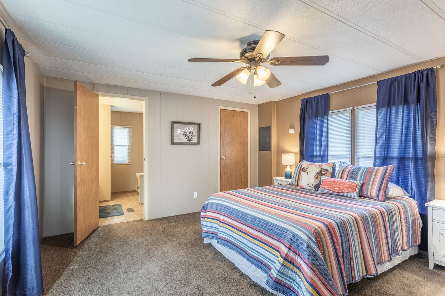 Guest house bedroom with a striped bedspread and blue curtains.