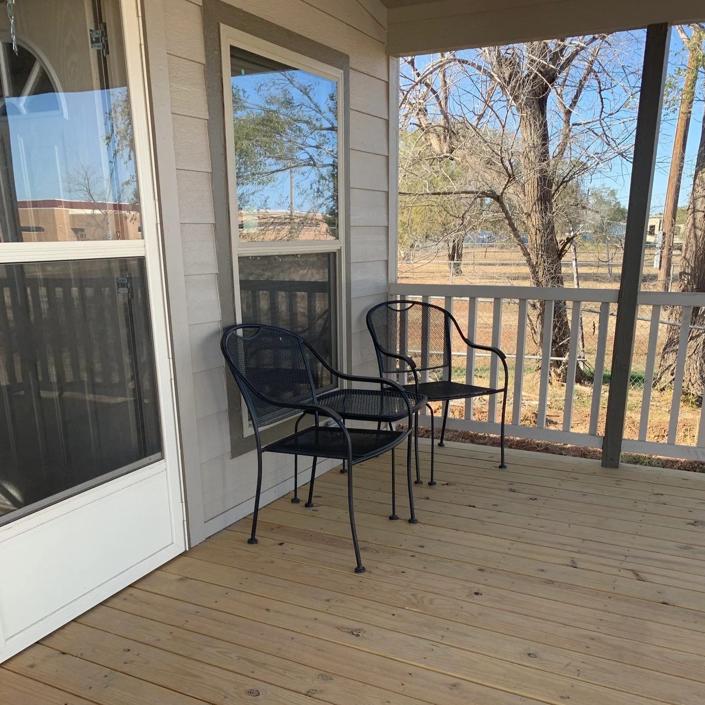 Tiny cabin porch with two metal chairs and a small table.