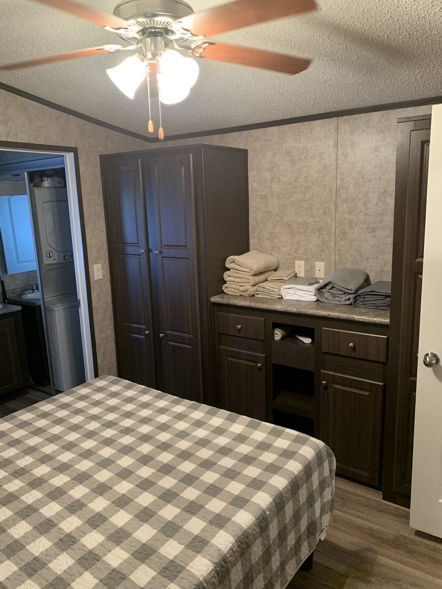 Tiny cabin bedroom with a wardrobe, a dresser and folded towels.