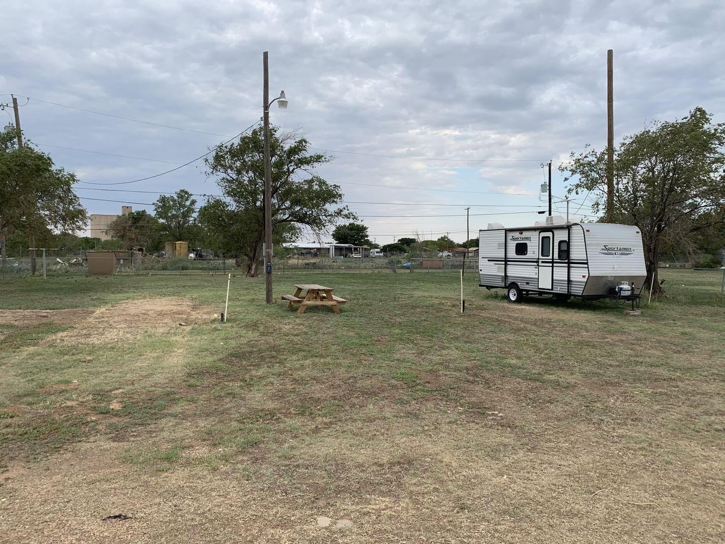 Travel trailer beside a picnic table and electrical pedestal at Windmill Ranch.
