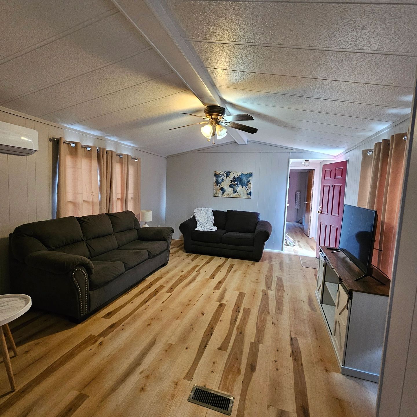 Guest house living room with a sofa, a loveseat, a TV and plank floors.