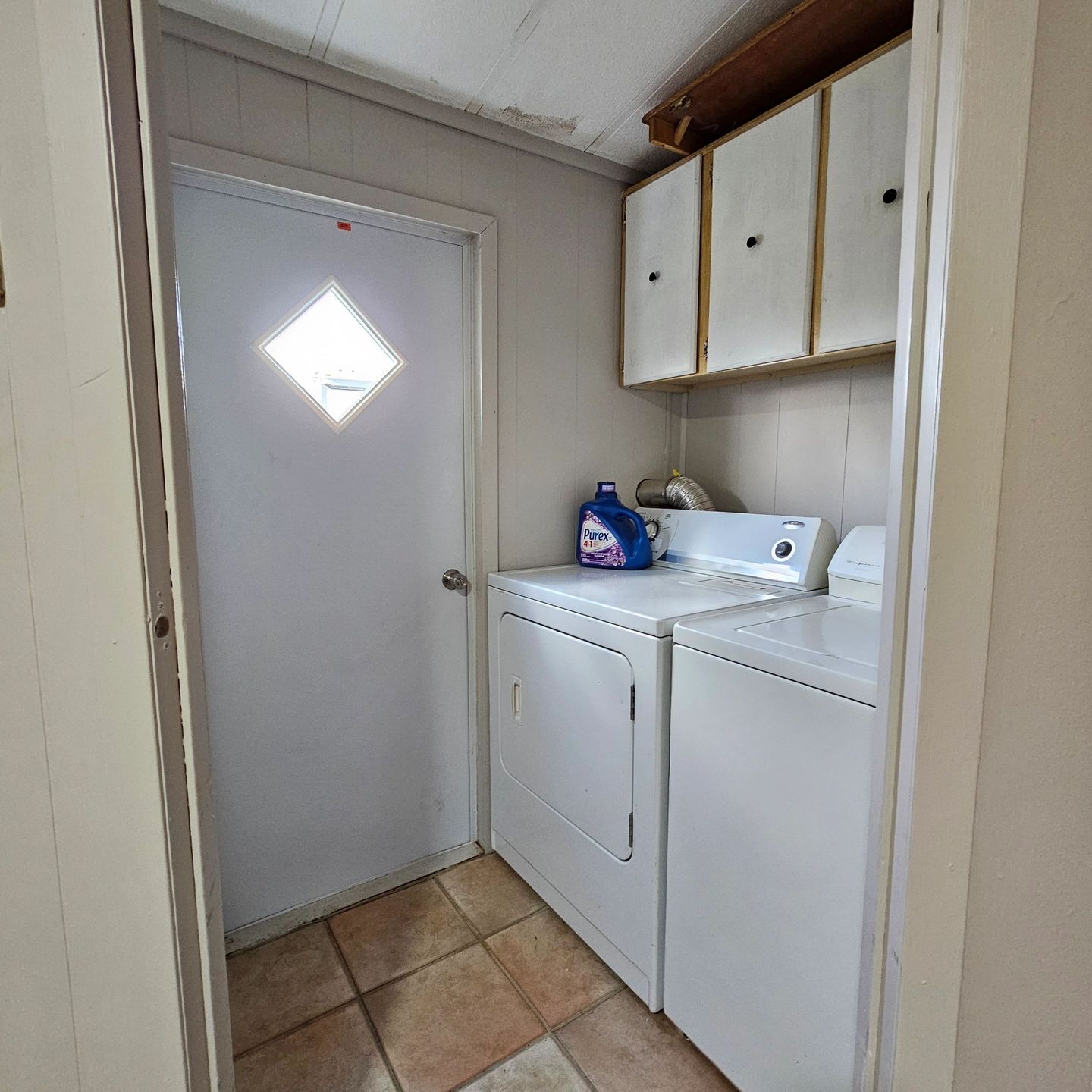 Washer and dryer side by side under white cabinets.