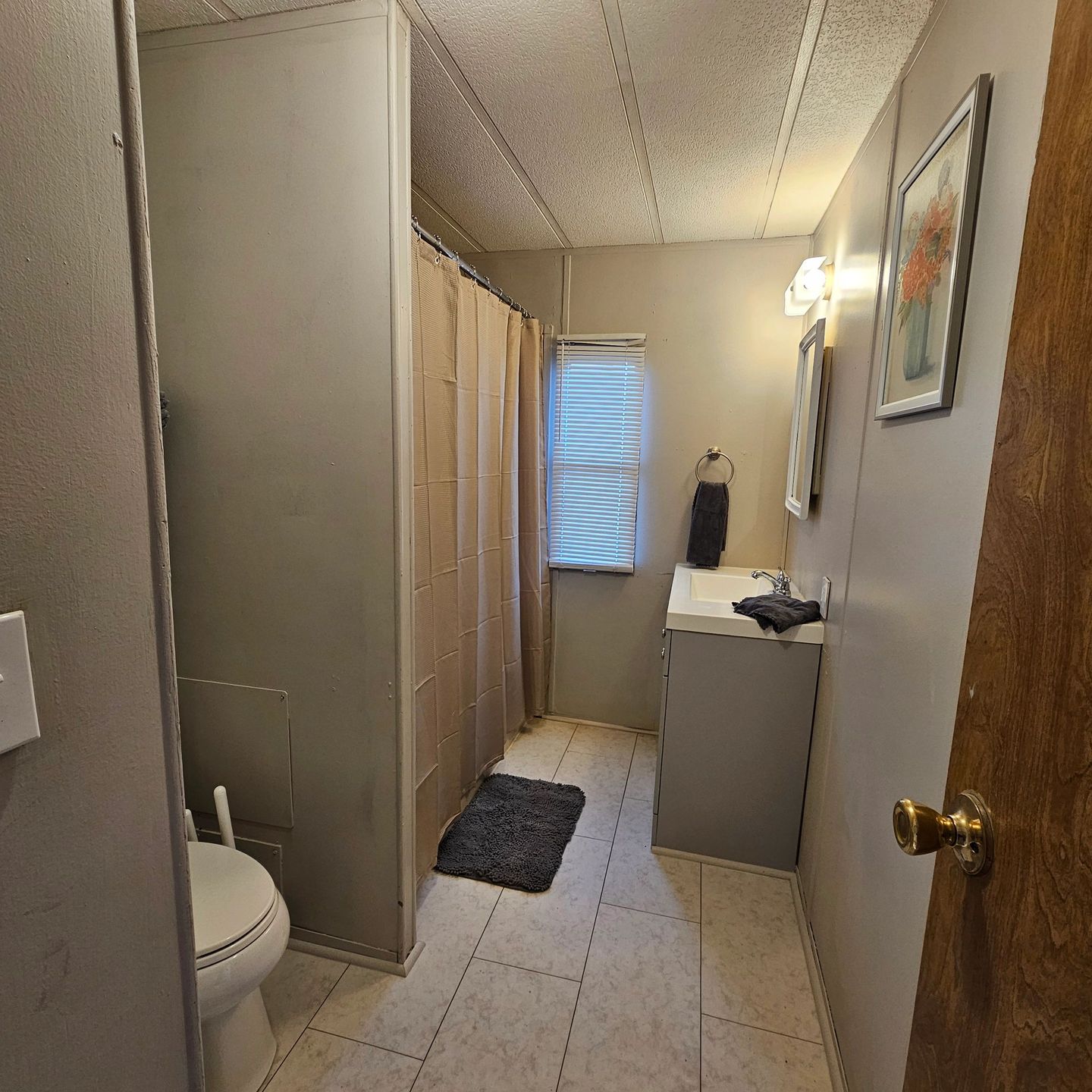 Guest house bathroom with a toilet, vanity and tile floor.