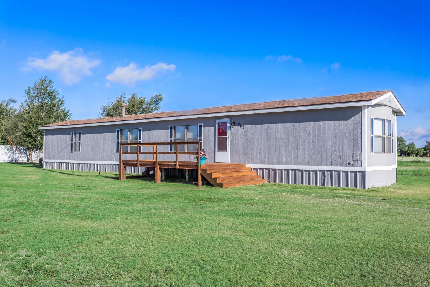Guest house with a wooden porch and lawn.